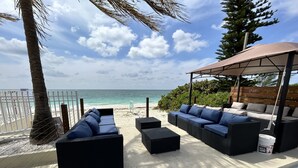 A beachside patio with outdoor furniture, a covered seating area, and a view of the ocean. - Beach Front Condo with Ocean View (Freeport)