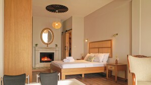 Une chambre avec un lit en bois, une cheminée, un grand miroir et deux chaises.