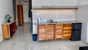 A compact kitchen with a tiled backsplash, wooden cabinets, a sink, and a black refrigerator.