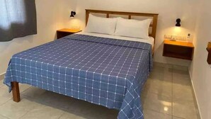 A neatly made bed with a blue checkered bedspread, two bedside tables with lamps, and abstract wall art above the bed.