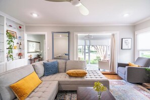 Un salon avec un canapé d’angle, une table basse et une vue sur l’extérieur grâce à une porte vitrée.