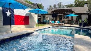 Een zwembad met een jacuzzi, ligbedden en parasols.