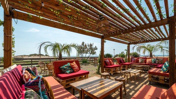 Un espace extérieur aménagé avec du mobilier en bois et une pergola au-dessus.