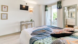 Une chambre à coucher avec un lit, un bureau, des chaises, une télévision et un balcon avec vue.
