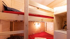 A bunk bed room with a red mattress, a white pillow, and a small white appliance, likely a heater or fan. - Les Alpages du Corbier C301 - Piscine partagée (Villarembert)
