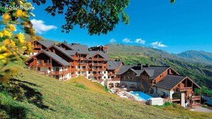 A mountain lodge with multiple wooden buildings, a swimming pool, and a view of the surrounding hills. - Les Alpages du Corbier C301 - Piscine partagée (Villarembert)