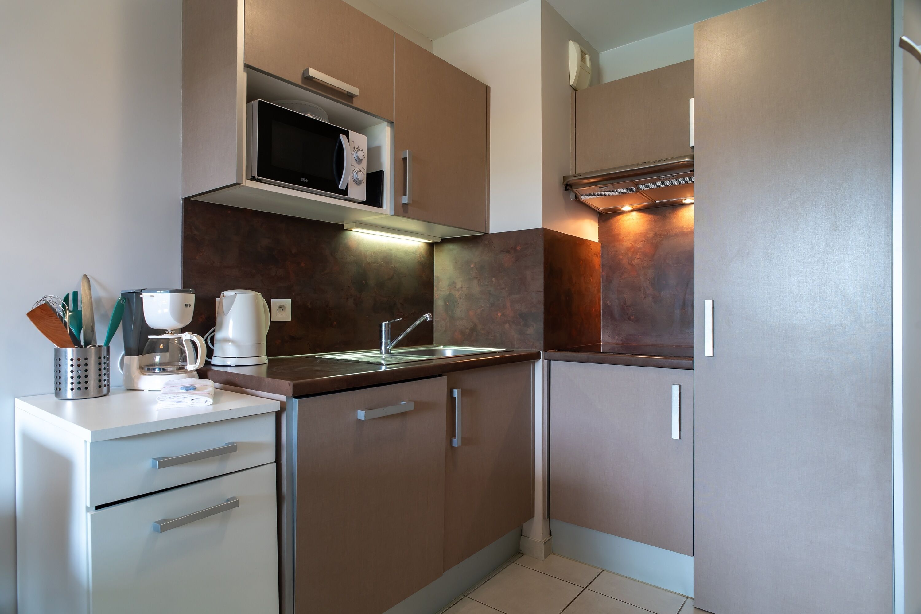 Una cucina moderna con elettrodomestici in acciaio inossidabile, un forno a microonde integrato e una macchina da caffè.