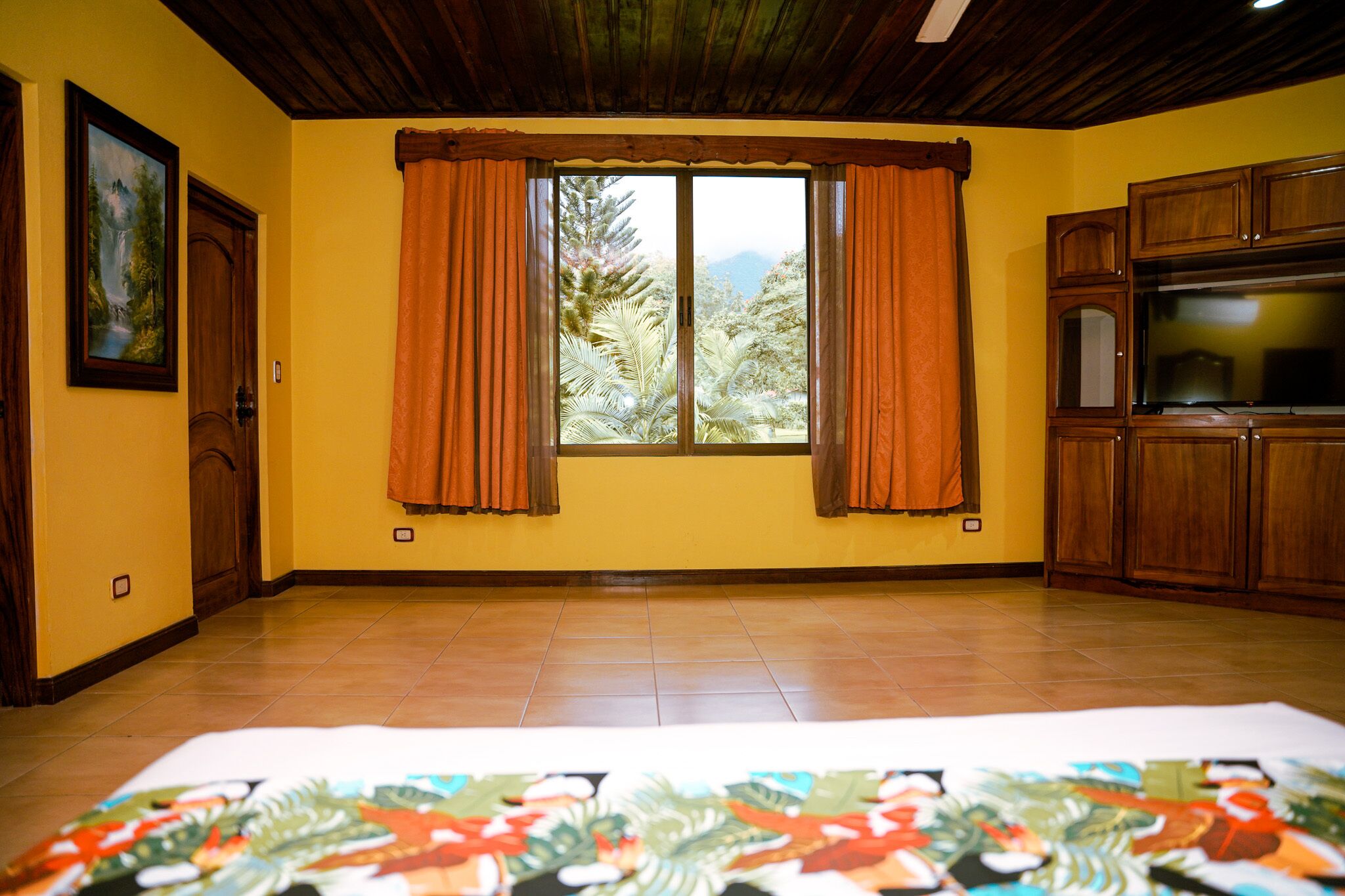 Una habitación con un ventanal grande, armarios de madera y un cuadro en la pared.