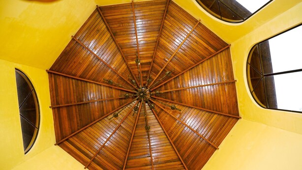 A room with a wooden ceiling fan, yellow walls, and large windows. - Mansion Arenal  (La Fortuna)