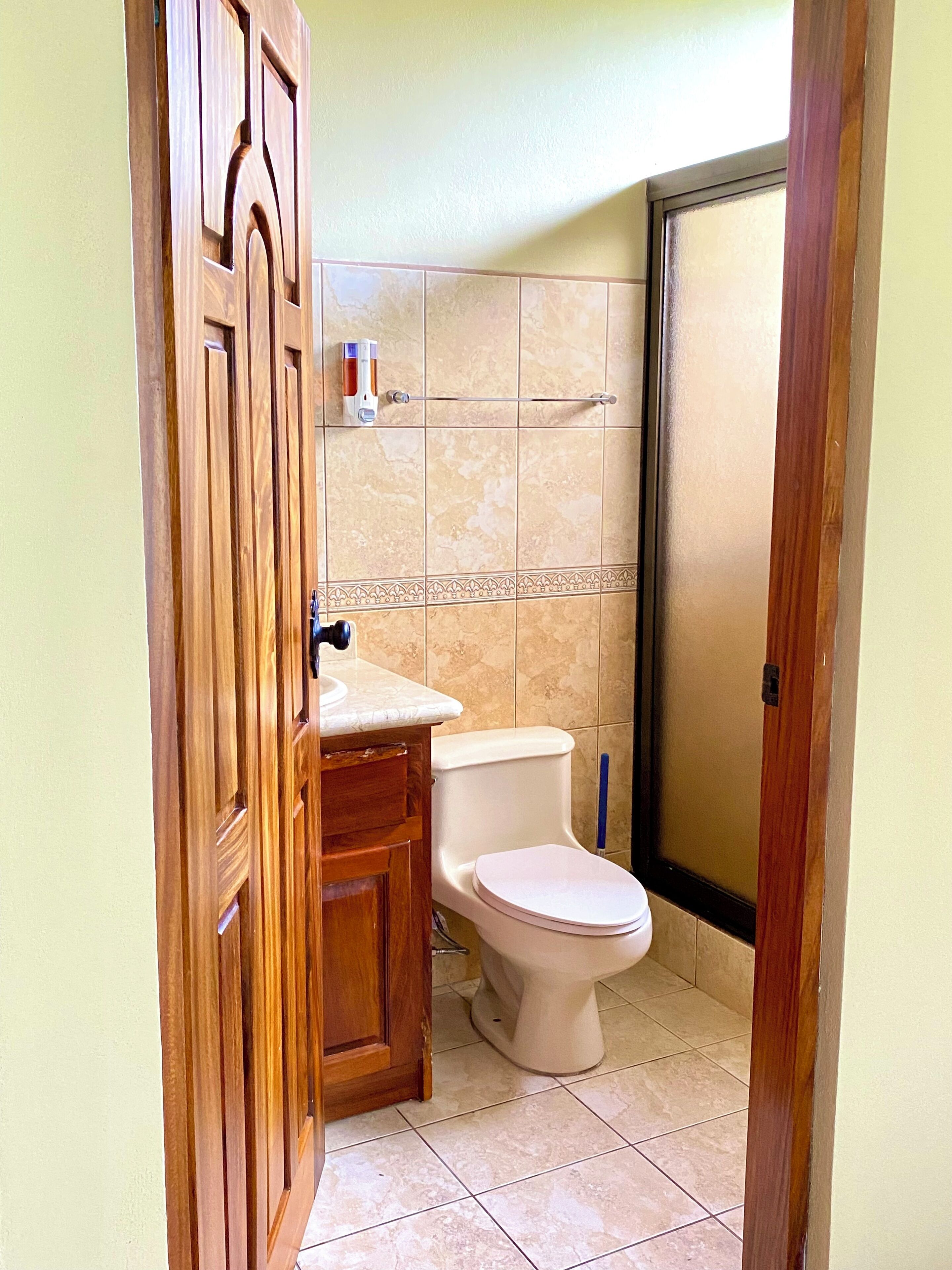 Un baño con tocador de madera, inodoro y zona de ducha.
