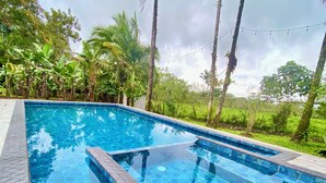 A rectangular swimming pool with a tiled edge, surrounded by a stone deck. - Mansion Arenal  (La Fortuna)