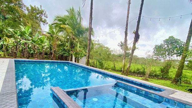 A rectangular swimming pool with a tiled edge, surrounded by a stone deck. - Mansion Arenal  (La Fortuna)