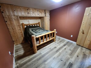 Een kamer met een houten bed, een schuine plafond en een bruine wand.