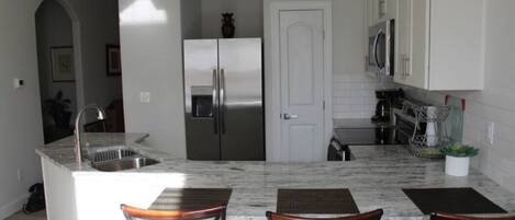 A modern kitchen with a central island, stainless steel appliances, and a microwave above the counter.