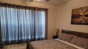 Quarto com uma cama grande, mesa de cabeceira, luminária e um quadro na parede.