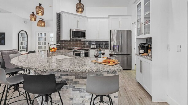 A modern kitchen with granite countertops, stainless steel appliances, and pendant lighting. - The Coral Reef Oasis (Cape Coral)