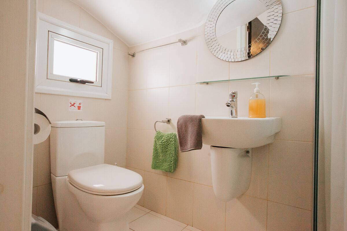 Un baño pequeño con inodoro, lavamanos, espejo y ventana.