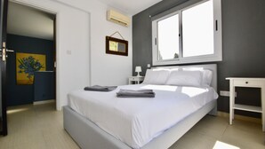 Une chambre à coucher comprenant un lit, une table de chevet, une fenêtre et une porte donnant sur une autre pièce.