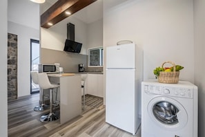 Une cuisine compacte équipée d’un lave-linge, d’un four à micro-ondes et d’une machine à café.