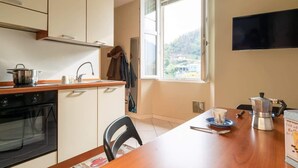 Eine Küche mit Herd, Backofen und einem Fenster mit Blick auf ein Haus und Bäume.