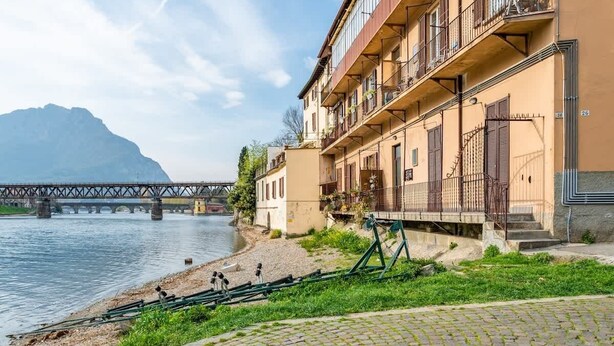 Ein Gebäude am Flussufer mit einer Brücke im Hintergrund.