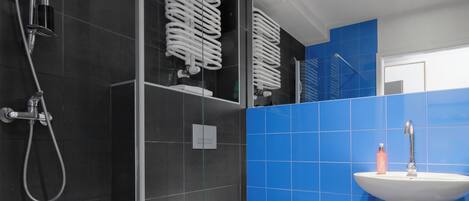 A modern bathroom with a glass-enclosed shower, a white toilet, and a sink with a mirror above it.