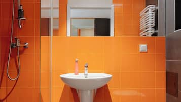 A bathroom with orange tiles, a white sink, and a shower.