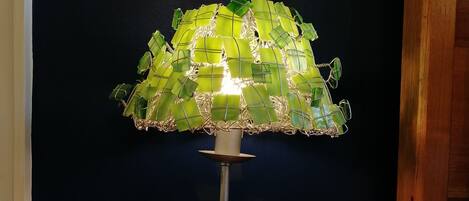 Una lámpara de pie con pantalla de vidrio verde sobre una mesa de madera, frente a una pared oscura.