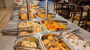 A buffet line with various food items including donuts, pastries, and other baked goods. - MAPP HOTEL (Aparecida)