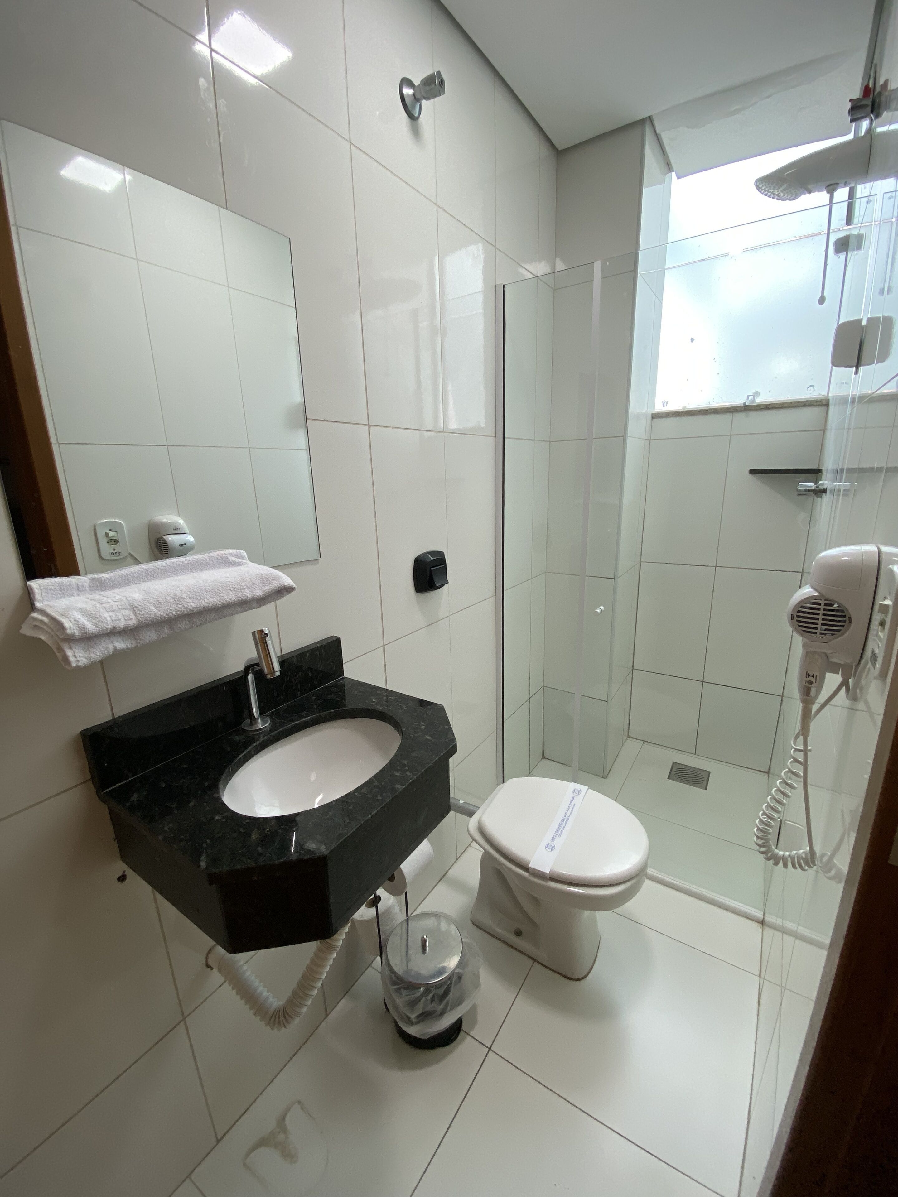 A modern bathroom with a black sink, white toilet, and a glass shower enclosure.