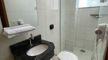 Un baño moderno con lavamanos negro, inodoro blanco y cabina de ducha de vidrio.