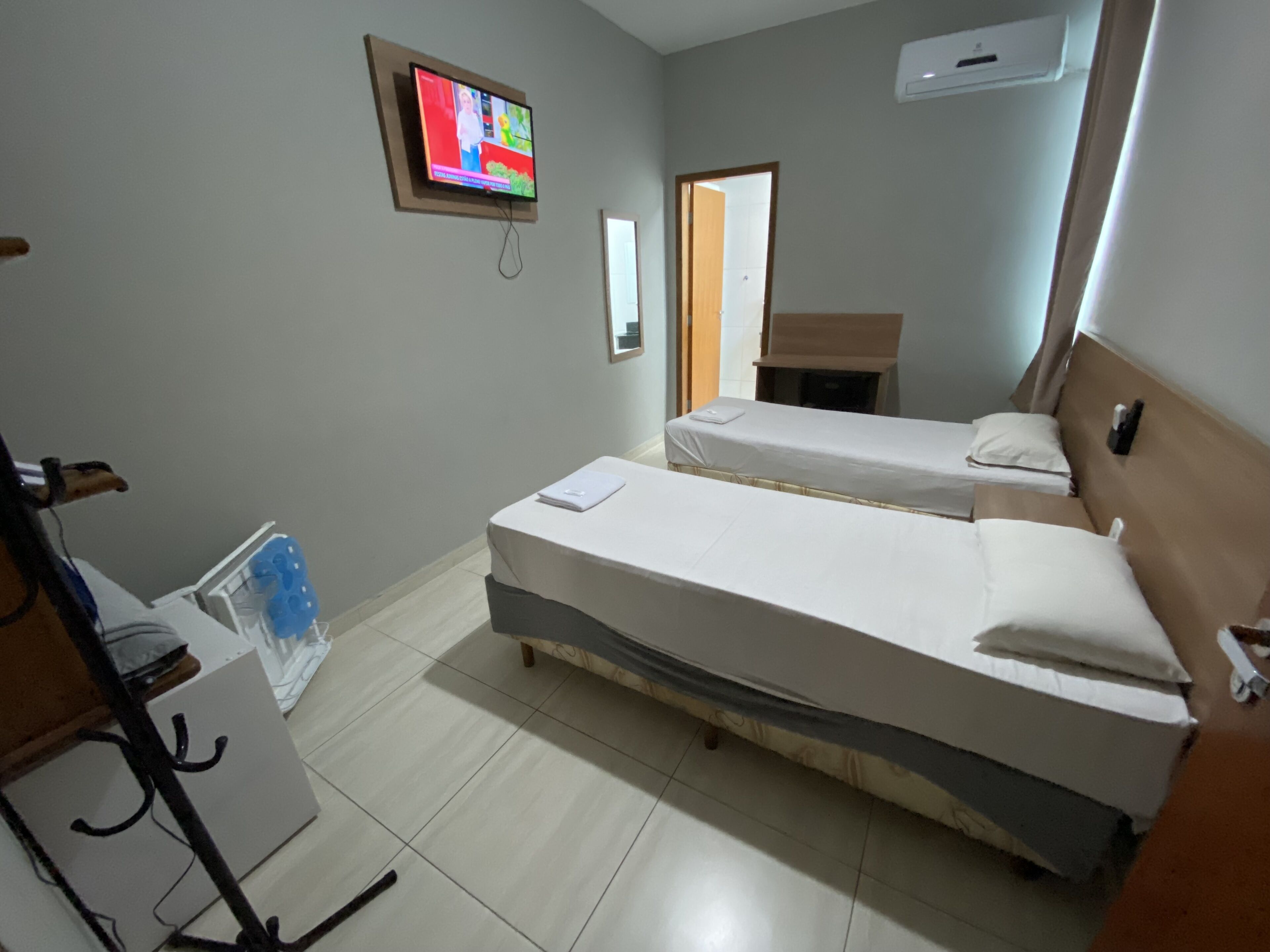 Habitación de hotel con dos camas, un televisor instalado en la pared, una mesita y una silla.