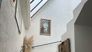 A staircase with a green vase and pampas grass on the wall, a vintage poster, and a rustic wooden piece. - Maison DE Ville Vallon DES Auffes (Marseille)