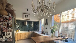 A modern kitchen with a wooden island, bar stools, a chandelier, and a herringbone tile backsplash. - Maison DE Ville Vallon DES Auffes (Marseille)