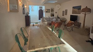 A dining area with a wooden table and green chairs, a sofa, and a TV. - Maison DE Ville Vallon DES Auffes (Marseille)