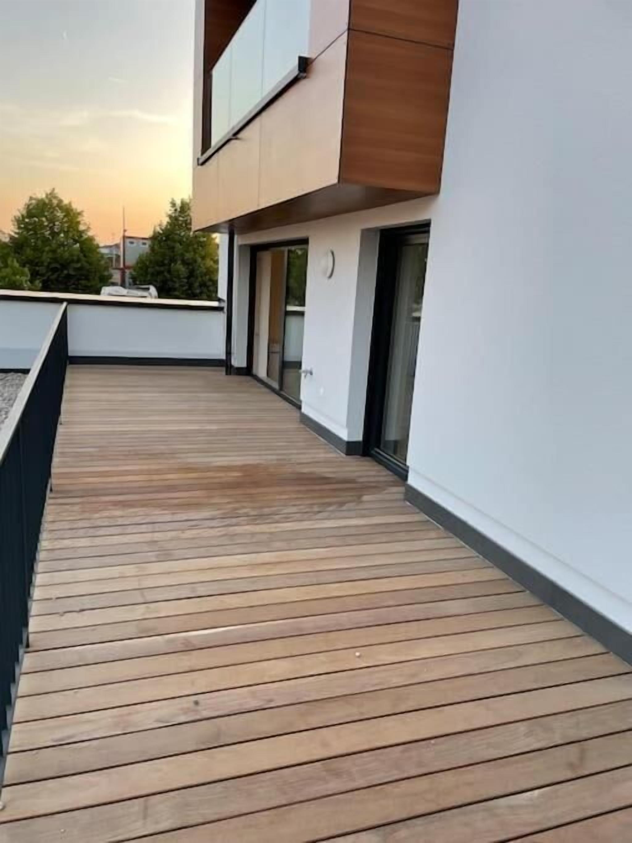 Un edificio moderno con terraza de madera y puerta de vidrio.