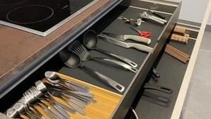 A kitchen with a built-in stovetop and a drawer organizer containing various utensils.