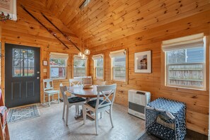 L’intérieur d’une cabane en bois comprend une table à manger, des chaises, un petit coin cuisine et une cage pour animaux de compagnie.