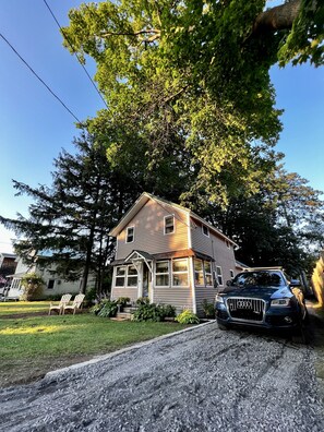 Une maison à deux étages avec un porche à l’avant et une allée.