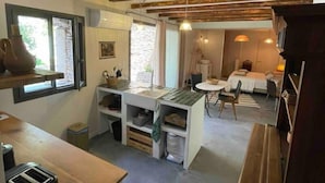 Une cuisine compacte dotée d’un îlot central intégré, un coin repas avec une table et des chaises, et un espace salon confortable avec un canapé.