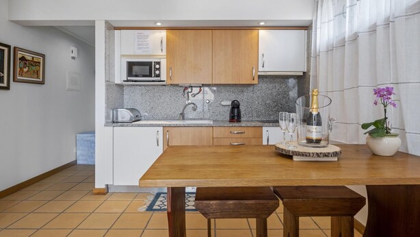 Una cocina moderna con una mesa de madera, microondas y cafetera.