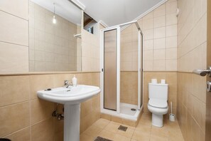 Une salle de bain avec un lavabo sur colonne, des toilettes et une douche à parois de verre.