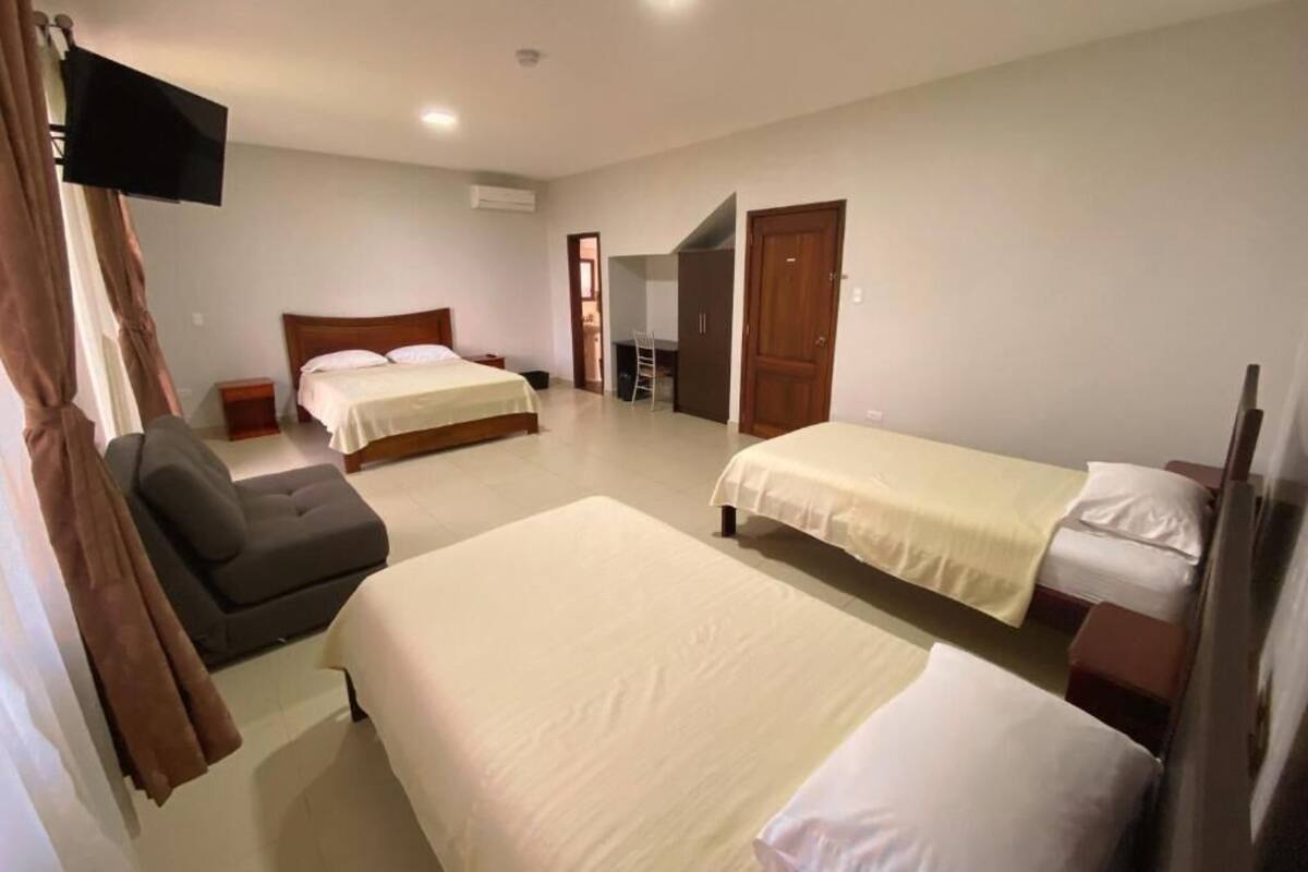 Une chambre d’hôtel avec deux lits, un canapé, une télévision et un bureau.