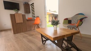 A modern kitchen with wooden cabinetry, a wooden dining table, and a colorful chair.