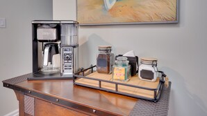 Un coin café avec une machine à café, un plateau avec des pots et un tableau accroché au mur.