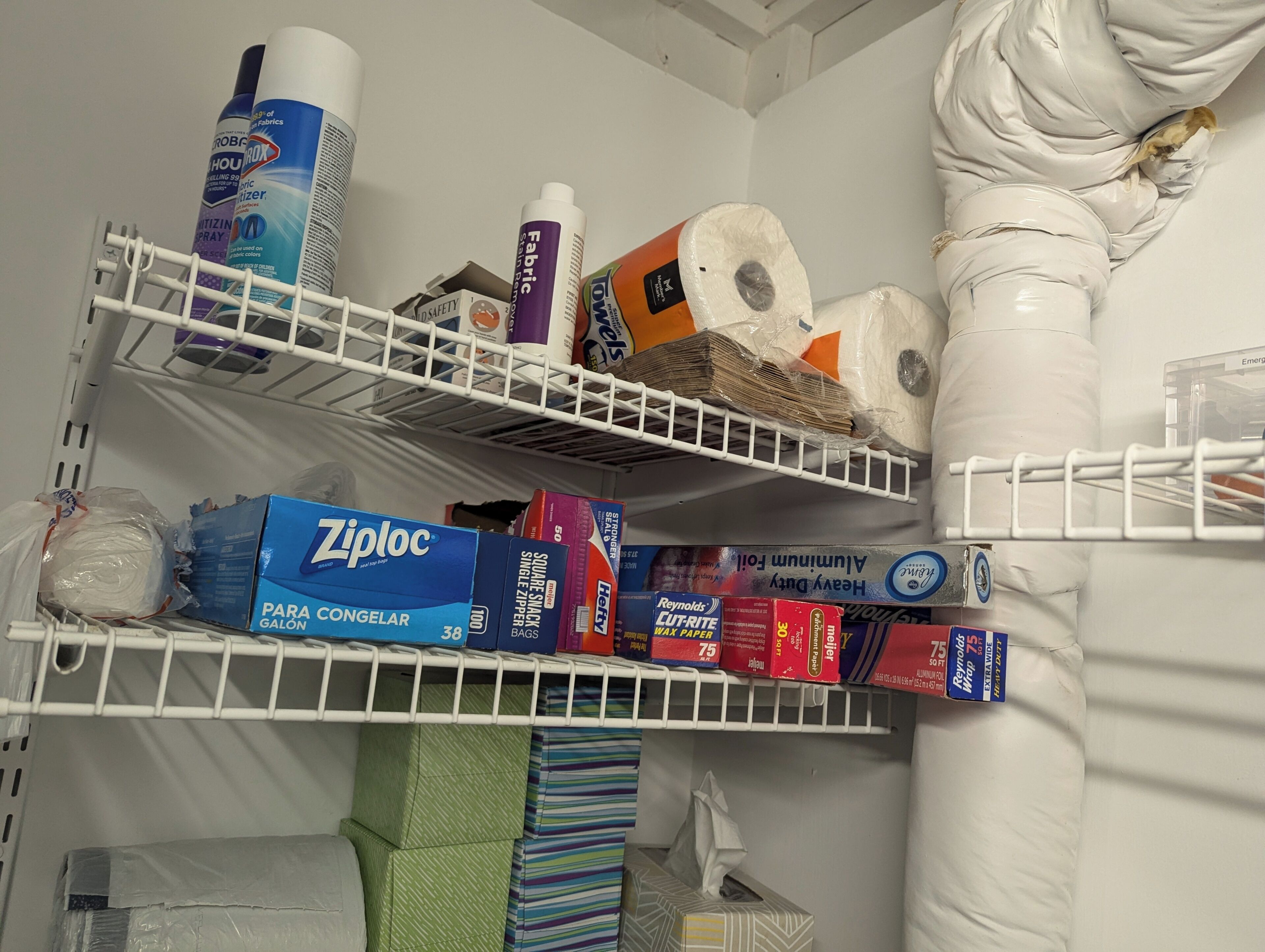 Un espace de rangement doté d’étagères contenant des produits de nettoyage, des articles en papier et des articles en tissu.