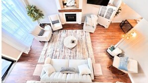 Un amplio salón con chimenea, sofás blancos y una mesa de centro.
