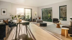 Ein modernes Wohnzimmer mit Essbereich, großen Fenstern und Blick auf Bäume.