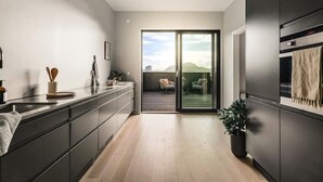 Eine moderne Küche mit einer Schiebeglastür, die auf einen Balkon mit Blick auf die Stadt führt.