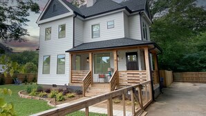 Een huis met twee verdiepingen, een overdekte veranda en een houten terras.